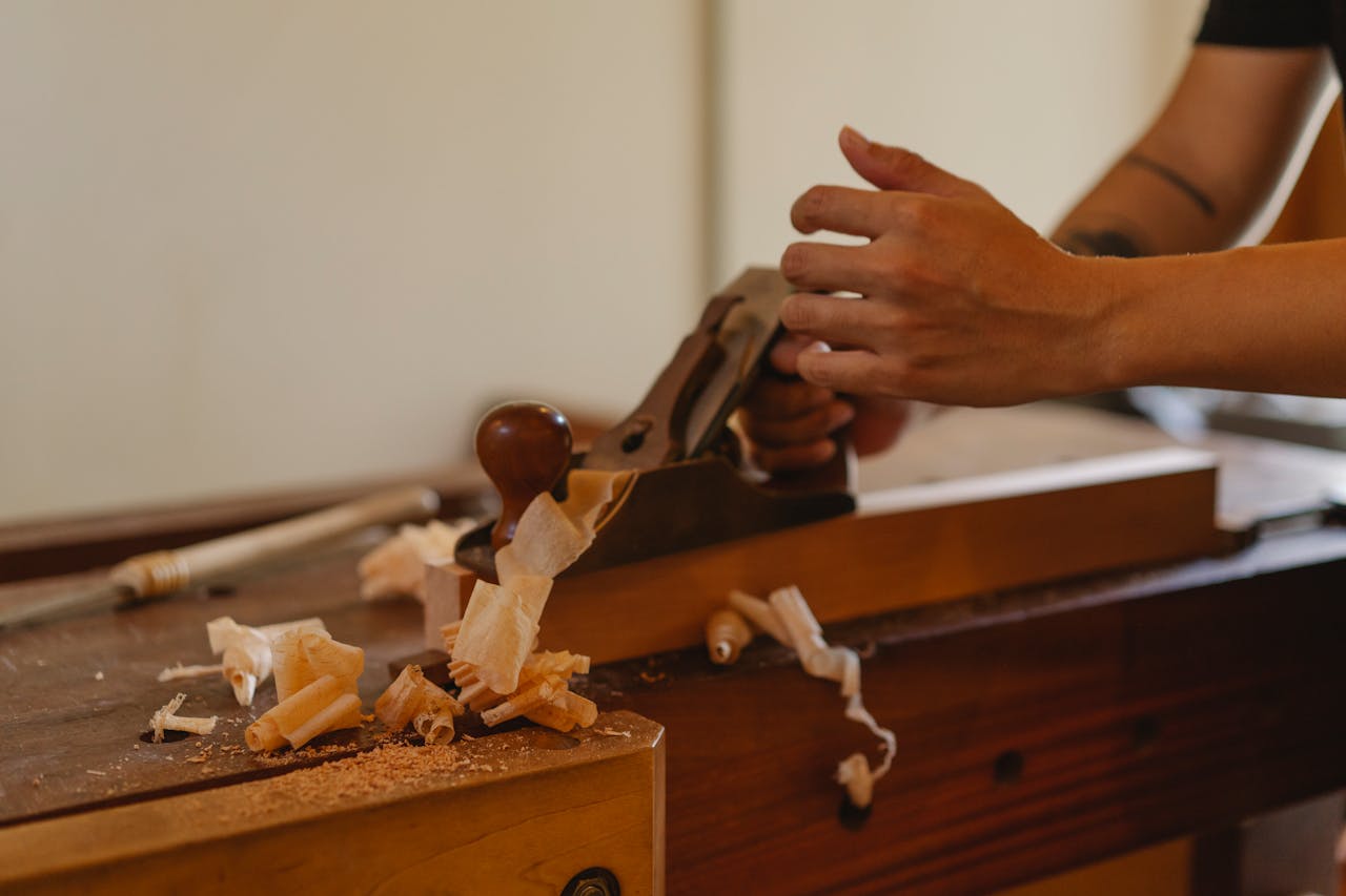 cta-02 Crop joiner shaping hardwood plank with jack plane working at table in modern workshop