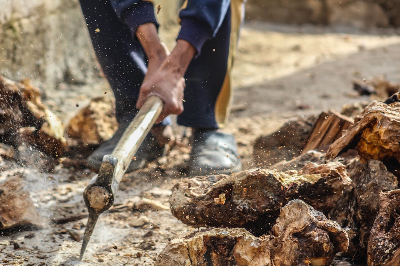programs-01 Close-up of a person chopping wood outdoors with an axe in Syria, capturing dynamic motion.